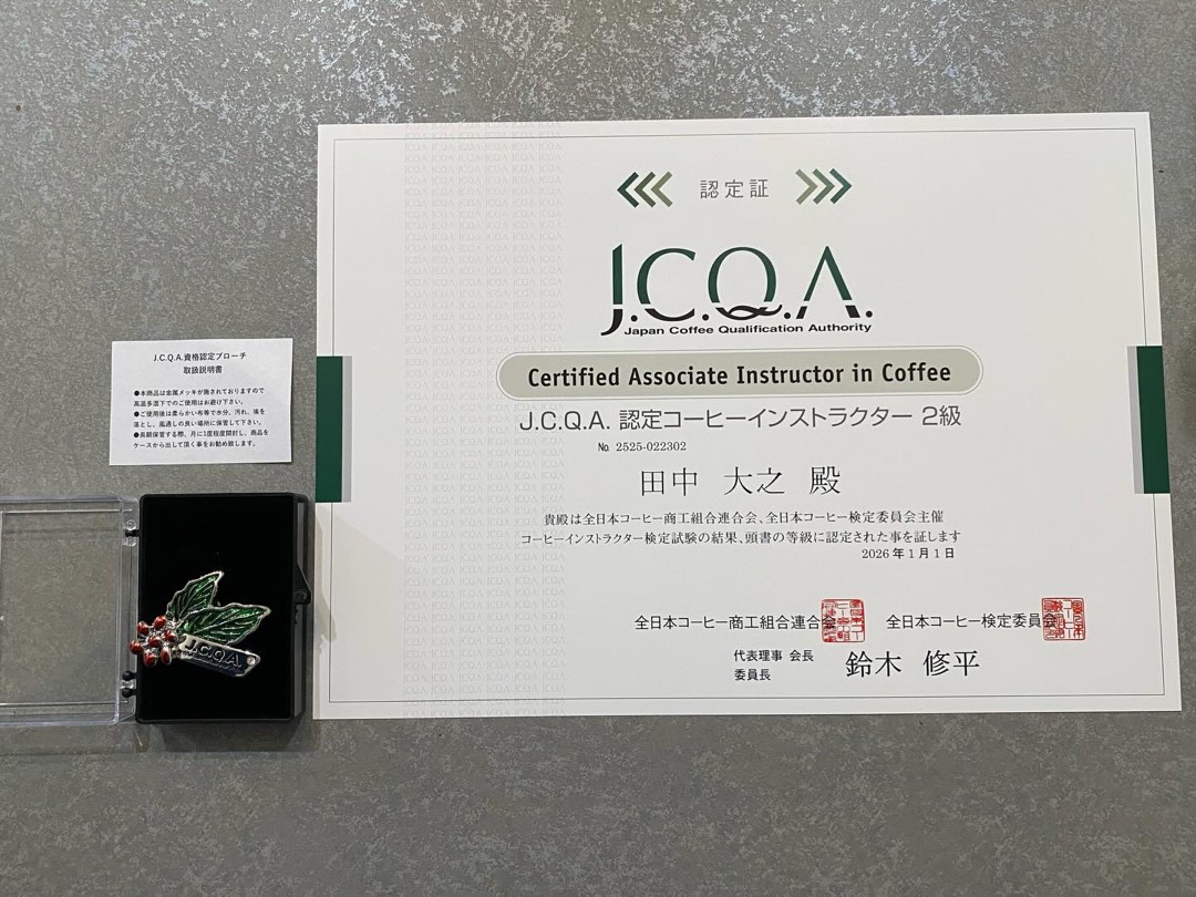 店主のJ.C.Q.A.認定コーヒーインストラクター2級の認定証と認定ブローチ